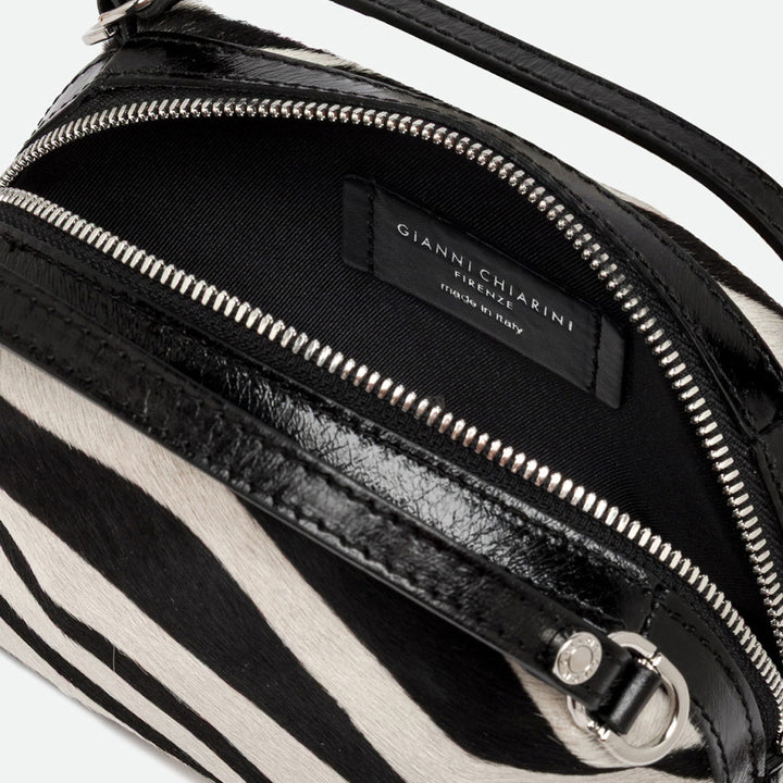 Inside a zebra print handbag showing a black lining and silver zip