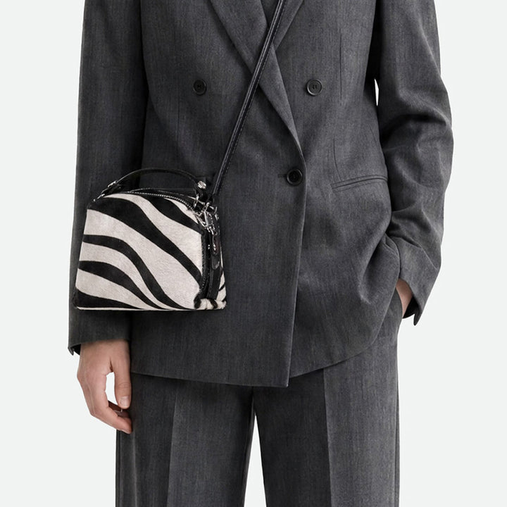 Woman in a grey suit wearing a small zebra print bag across the body