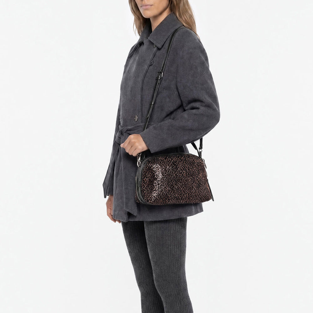 Woman in a grey jacket wearing a bronze sequinned bag across the body