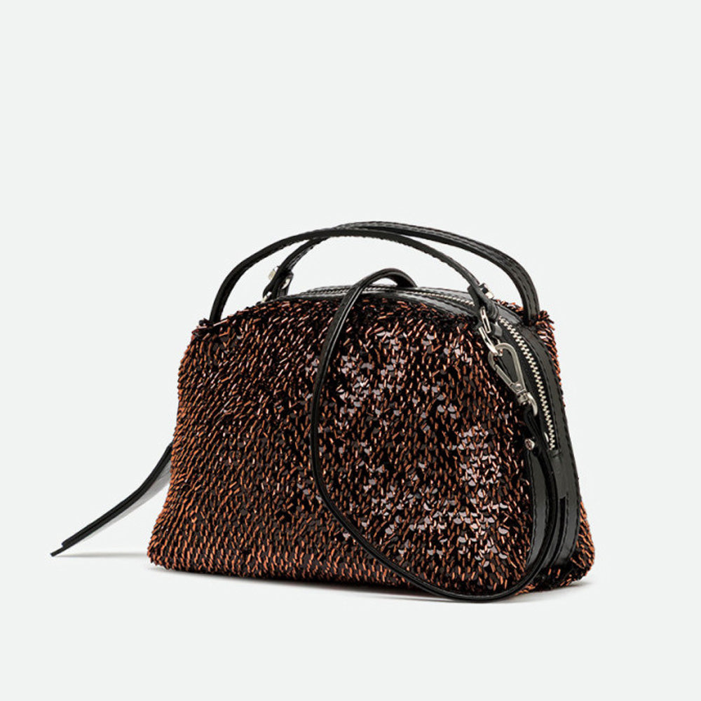 Angled view of a bronze sequinned handbag with its crossbody strap attached