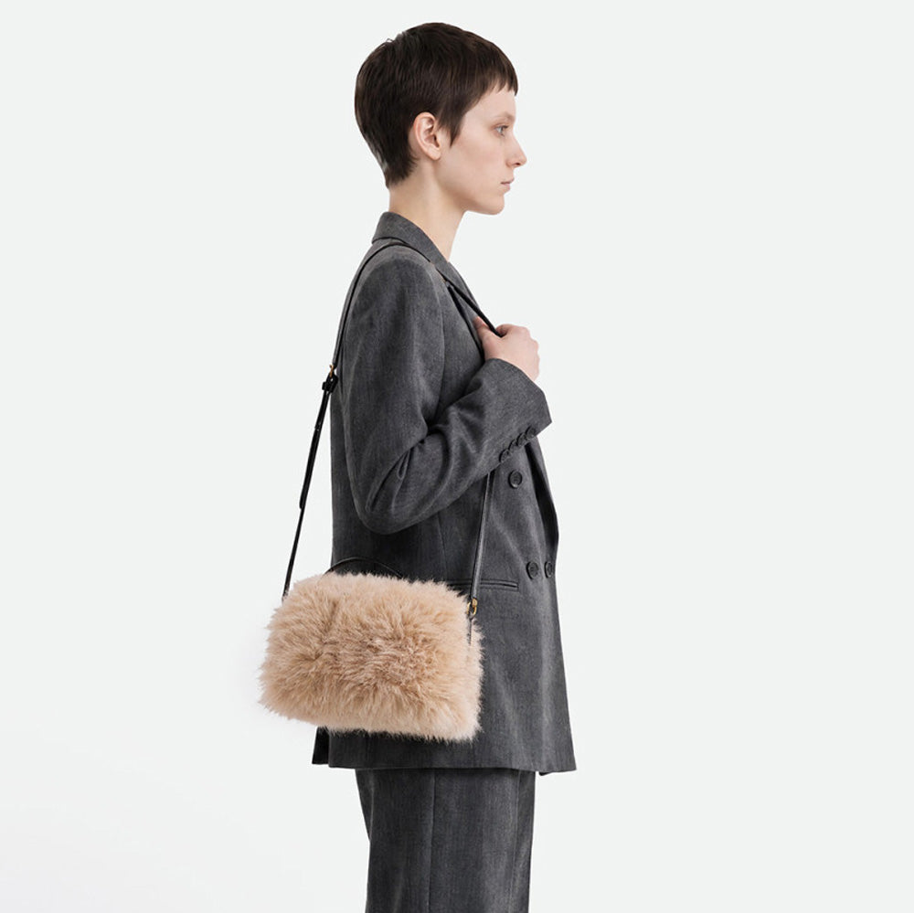 Woman in a grey blazer wearing a cream faux fur bag across the body