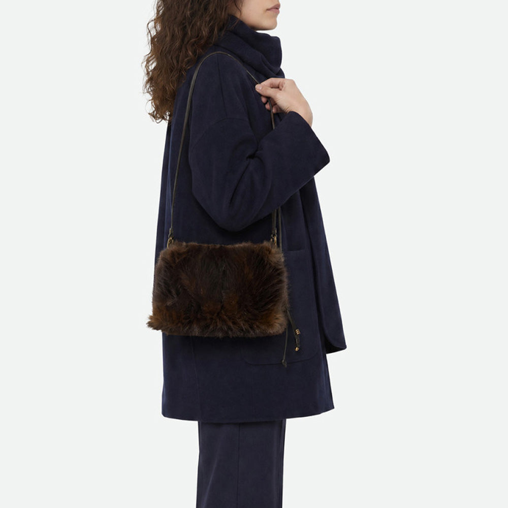 Woman in a navy coat wearing a brown faux fur bag across the body