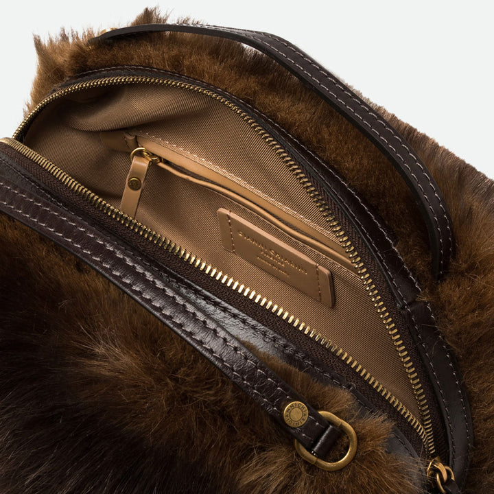 Inside a brown faux fur bag showing a tan lining and zip pocket