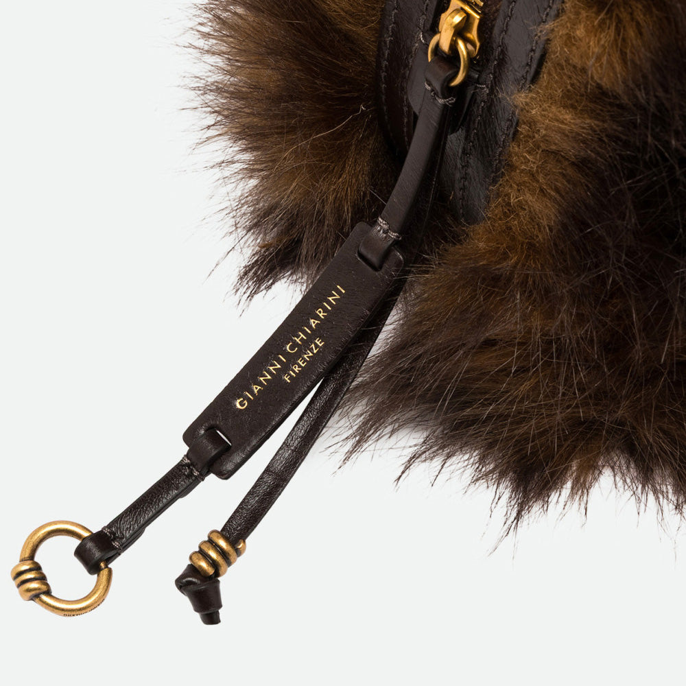 Close-up of brown faux fur with a dark leather strap and antique gold ring
