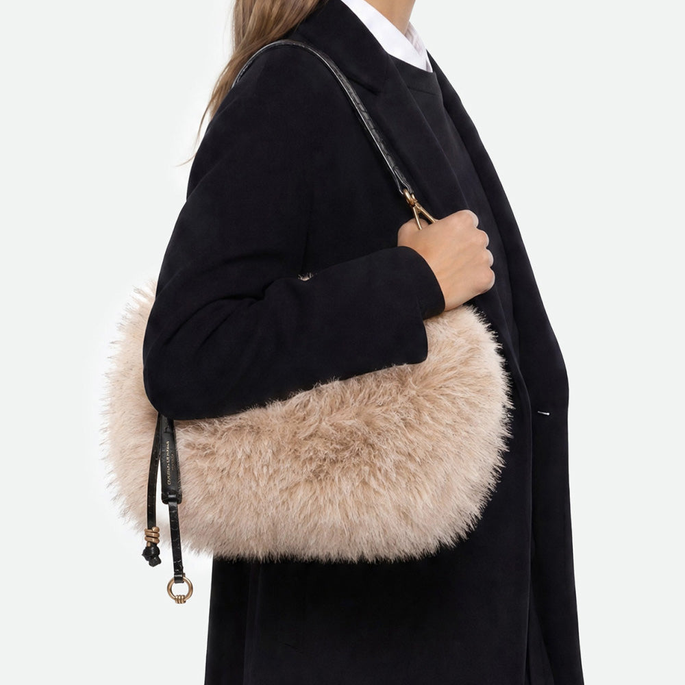 Woman in a black coat wearing a cream faux fur bag on her shoulder