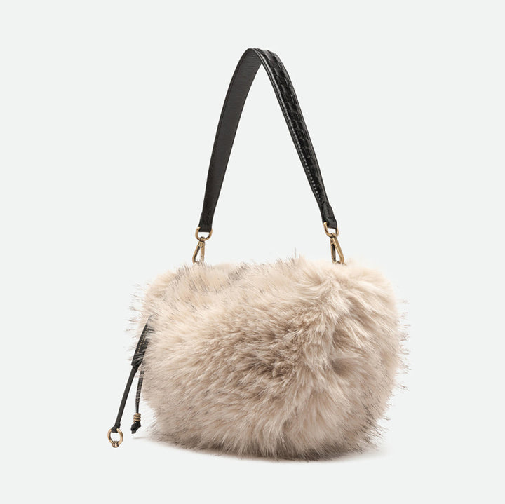 Side view of a cream faux fur shoulder bag with a black leather strap