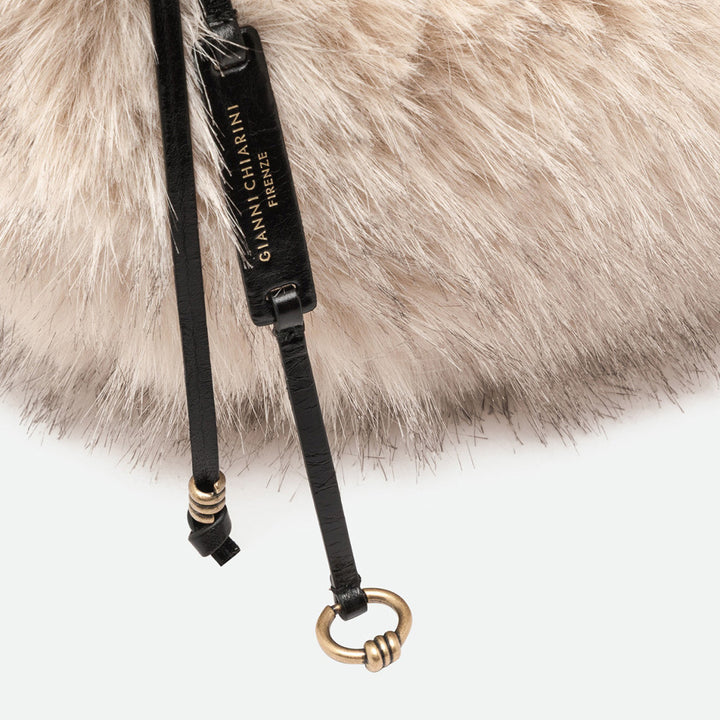 Close-up of fluffy cream faux fur with a black leather strap and gold ring