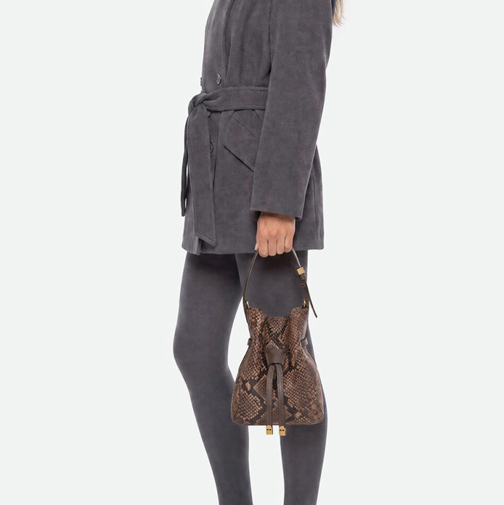 Woman in grey tights carrying a small brown snake print bucket bag