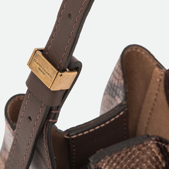 Close-up of a gold buckle on the brown leather strap of a snake print bag