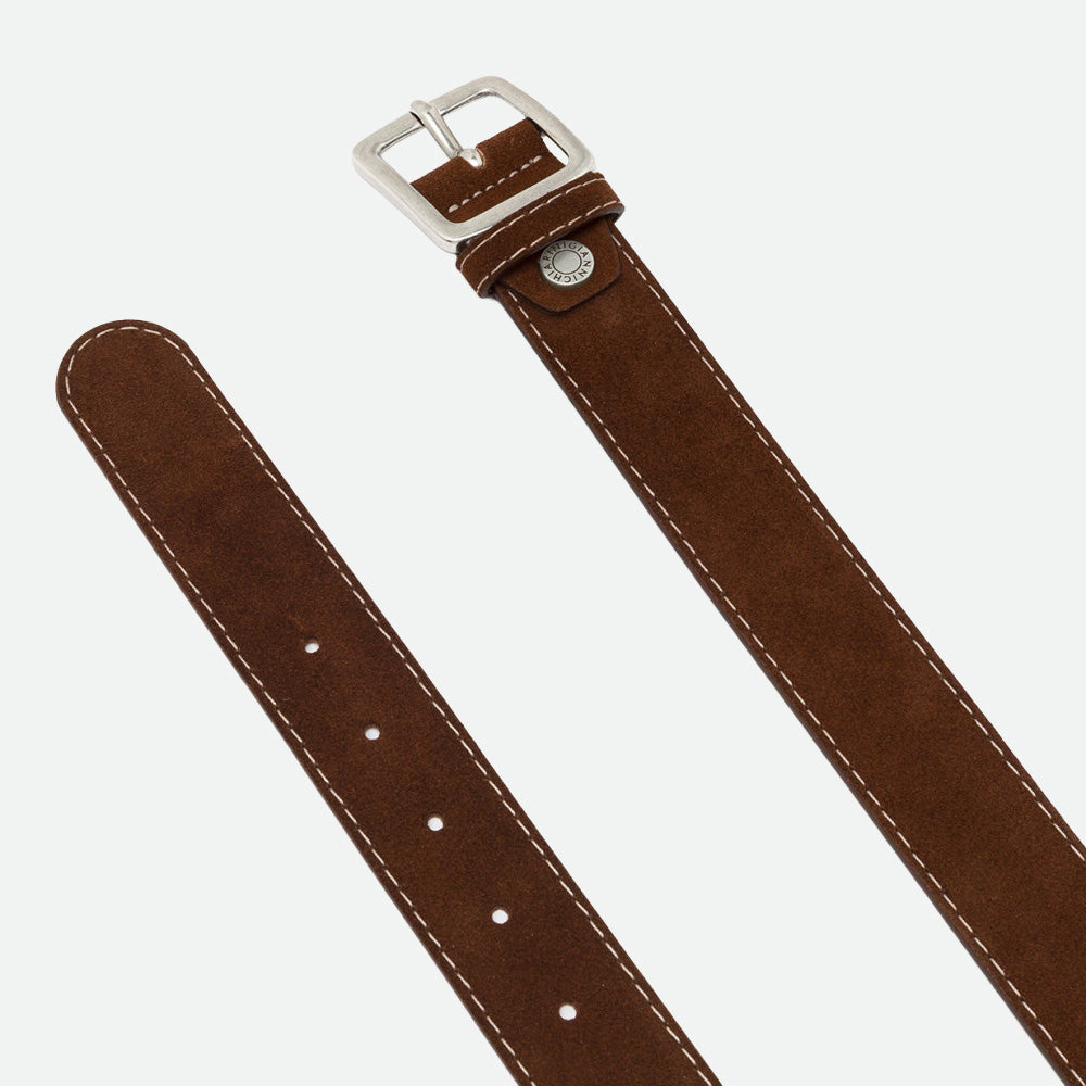 Close-up of a brown suede belt showing the silver buckle, stud and punched holes
