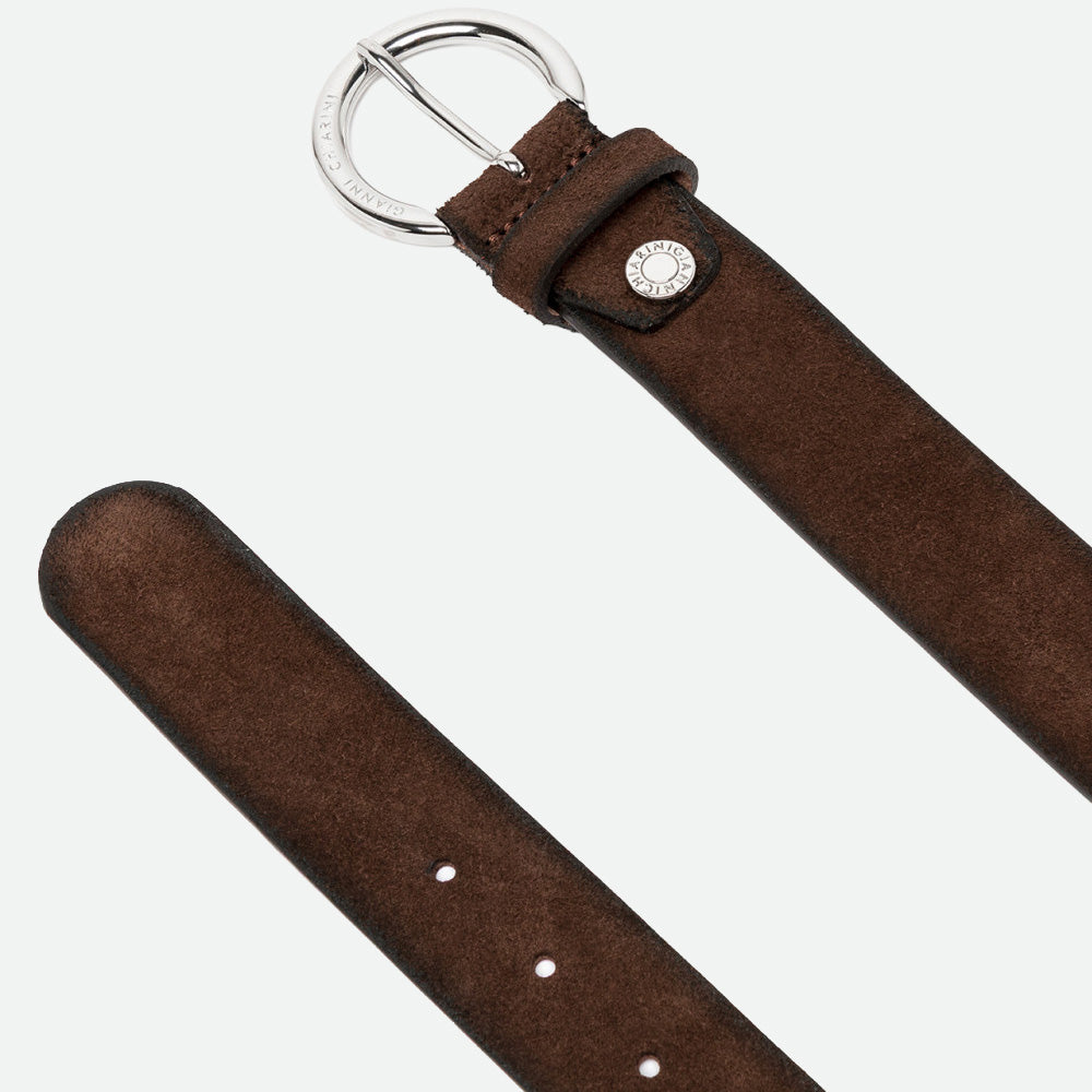 Close-up of a dark brown suede belt with a rounded silver buckle and punched holes