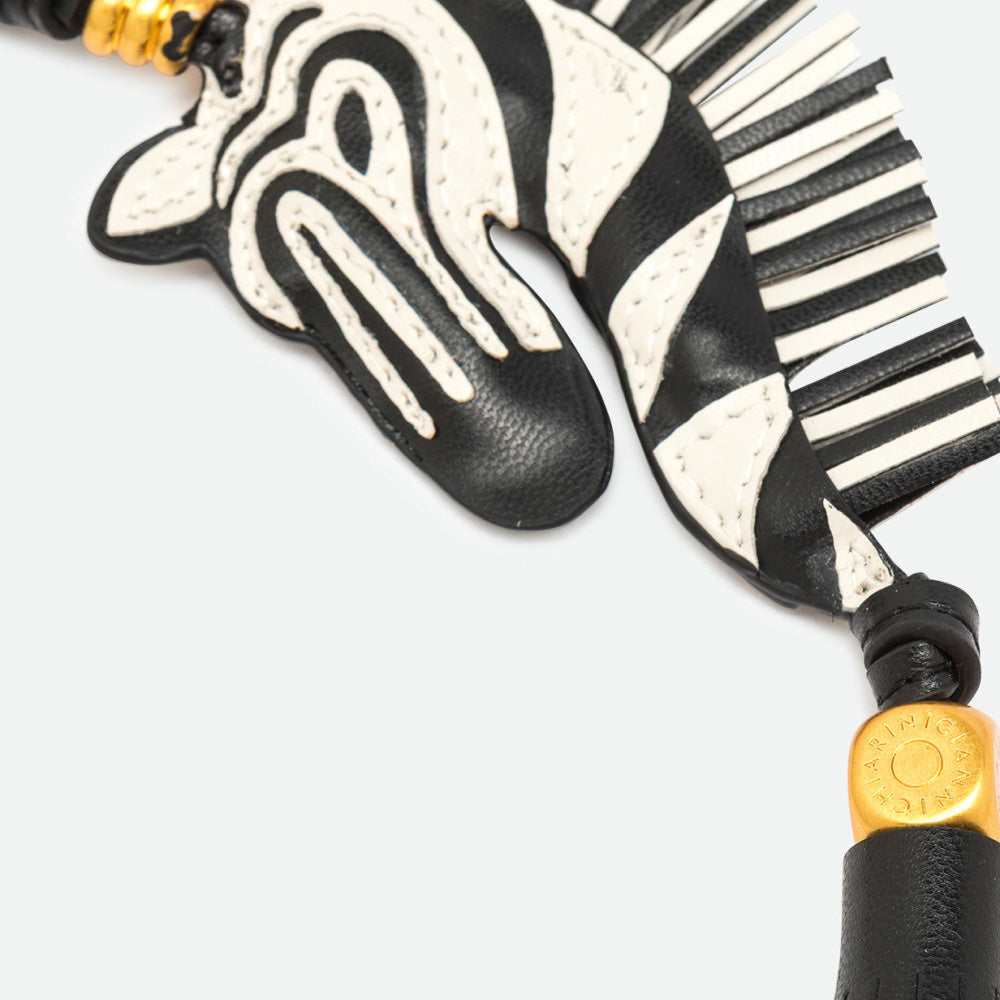 Close-up of a black and cream zebra bag charm showing its stripes and fringed mane