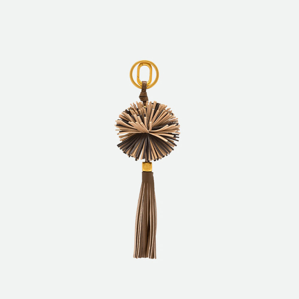 Reverse side of a lion bag charm showing its fringed mane and tassel
