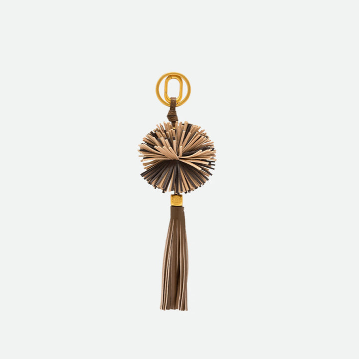 Reverse side of a lion bag charm showing its fringed mane and tassel