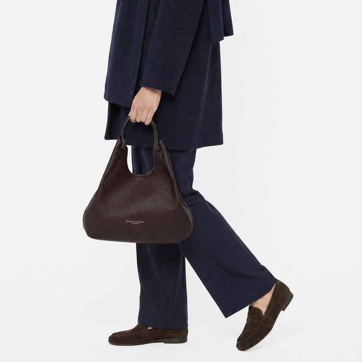 Woman in navy trousers carrying a dark brown leather tote bag