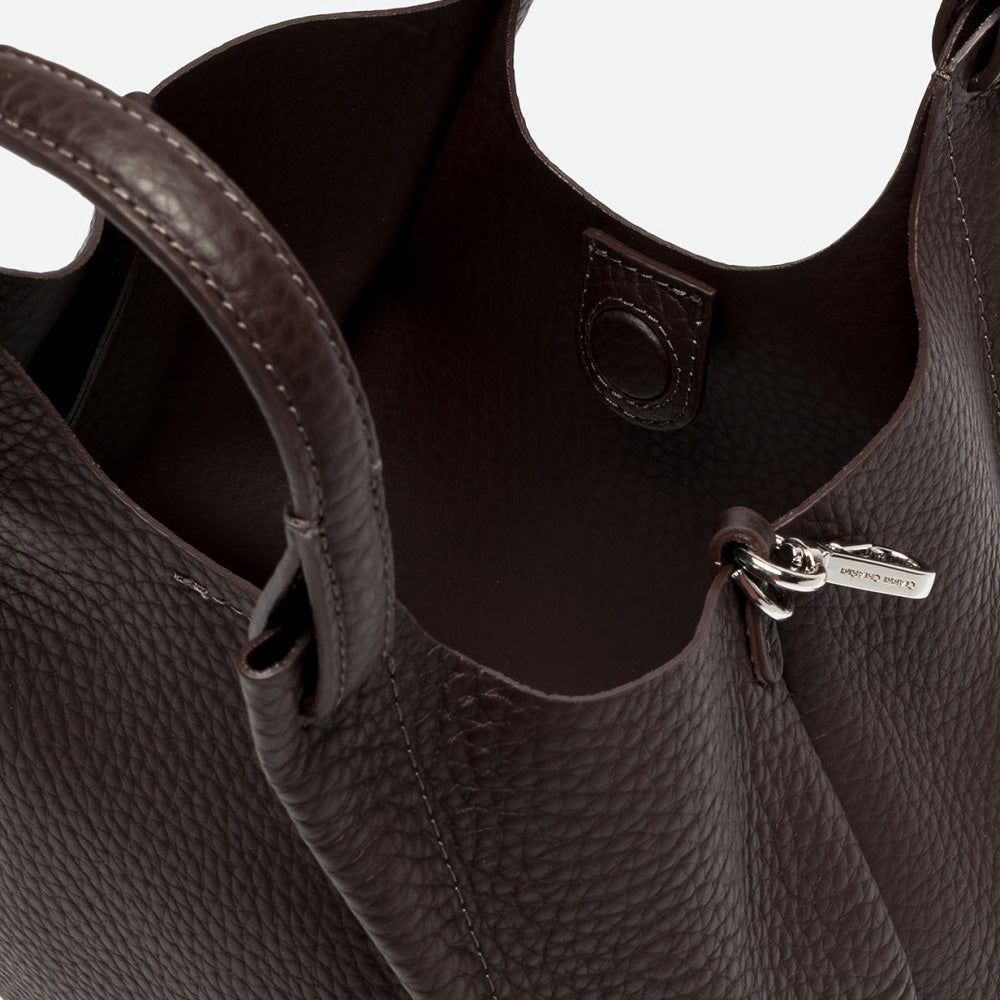 Inside a dark brown leather tote showing the interior and magnetic clasp
