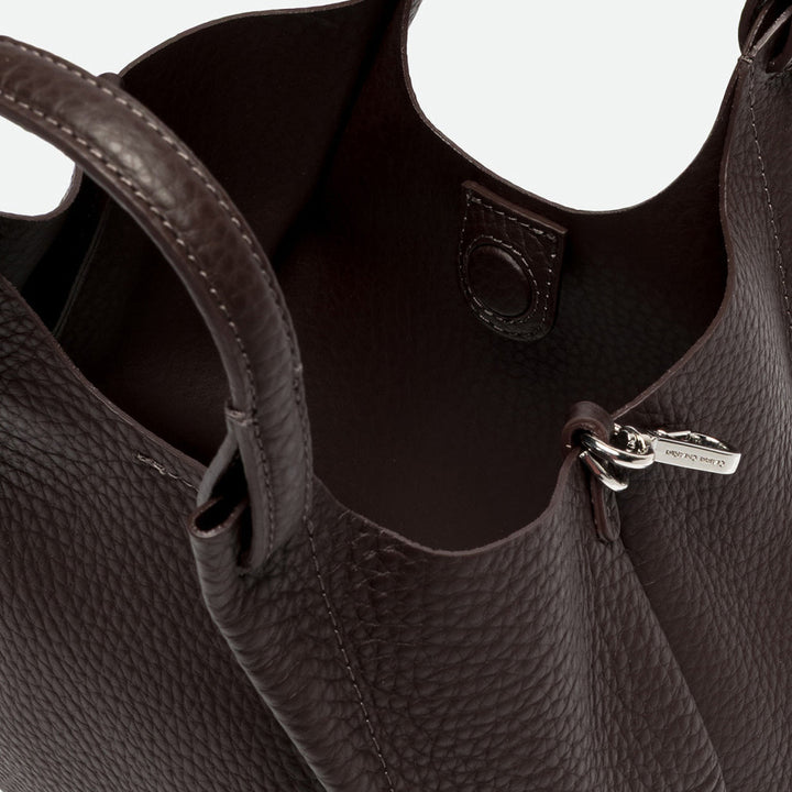 Inside a dark brown leather tote showing the interior and magnetic clasp