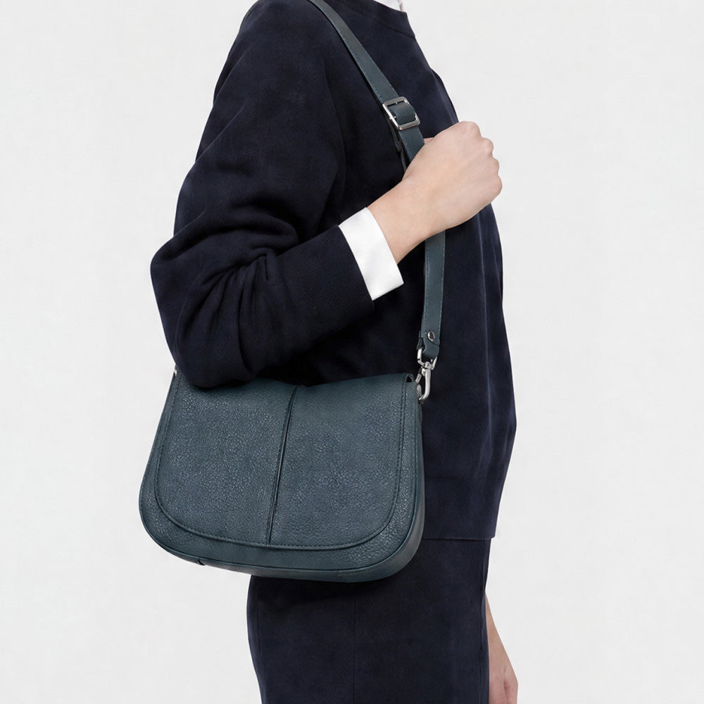 Woman in a navy jumper wearing a dark green leather shoulder bag
