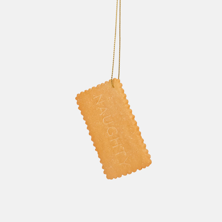 Golden rectangular biscuit ornament with crinkled edges and the word Naughty pressed into the sparkly surface