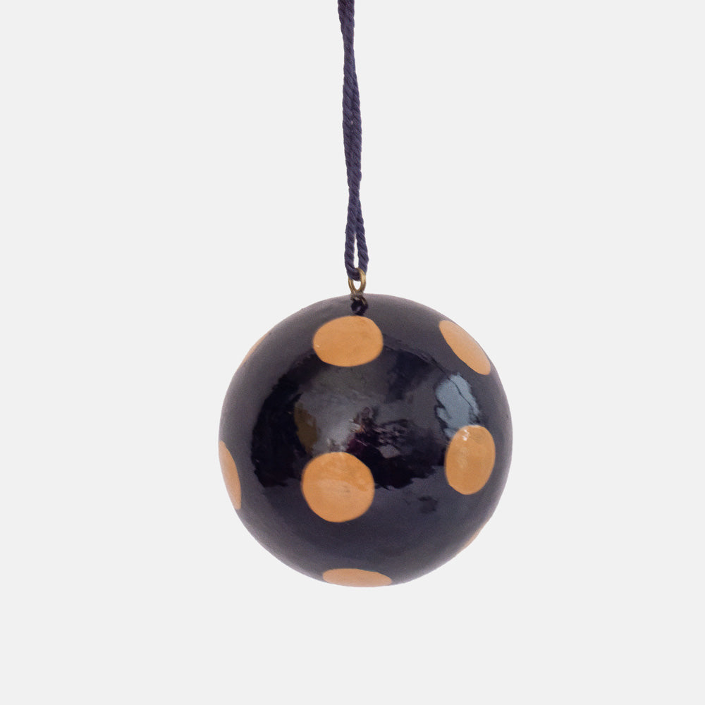 Glossy navy round bauble with large nude pink dots, hanging from a navy cord