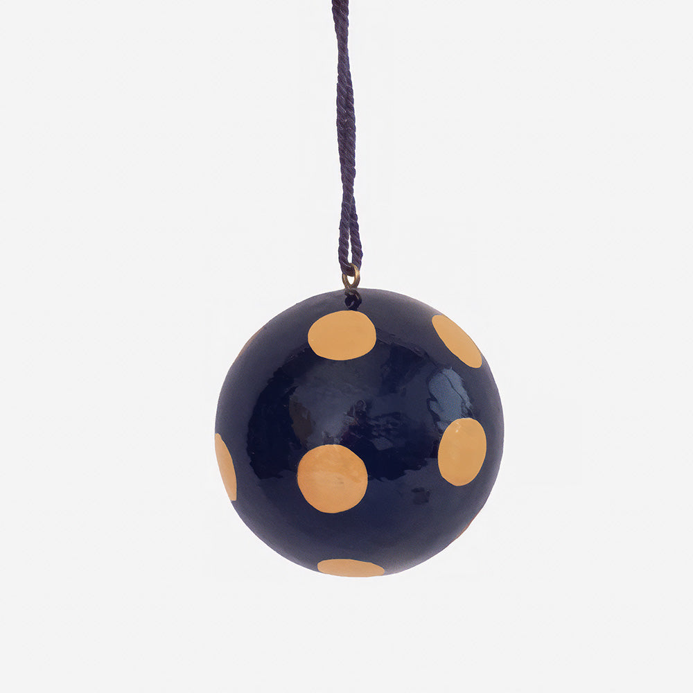 Glossy navy round bauble with large nude pink dots, hanging from a navy cord