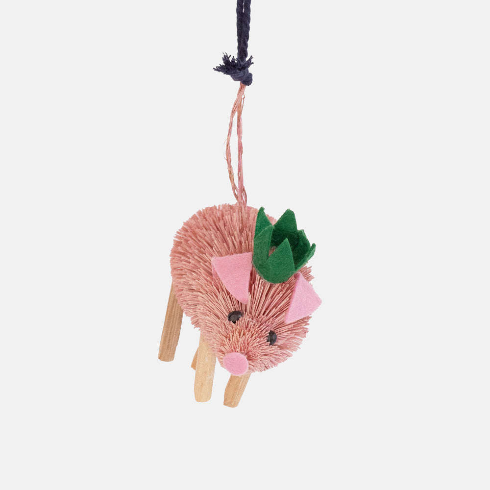 Pink bristle pig ornament with wooden legs, pink felt ears and a green felt party crown, on a pink and navy cord