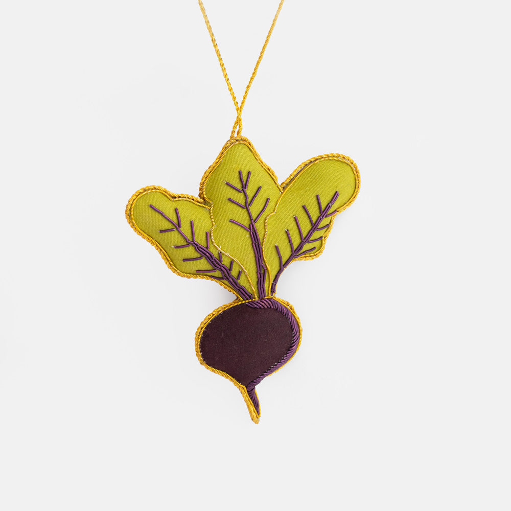 Embroidered beetroot Christmas tree decoration with a purple root and lime green leaves, outlined in gold thread and hanging from a gold cord.