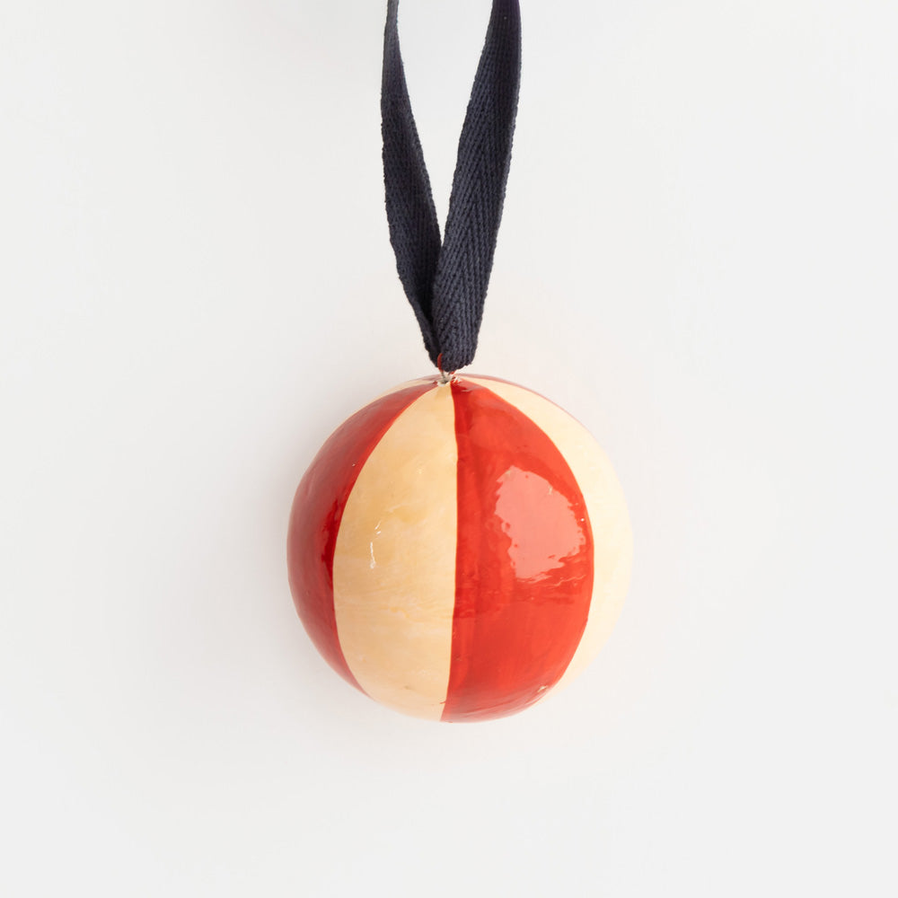 Pale pink and red stripe hand painted papier-mâché Christmas bauble with a navy ribbon hanging loop.