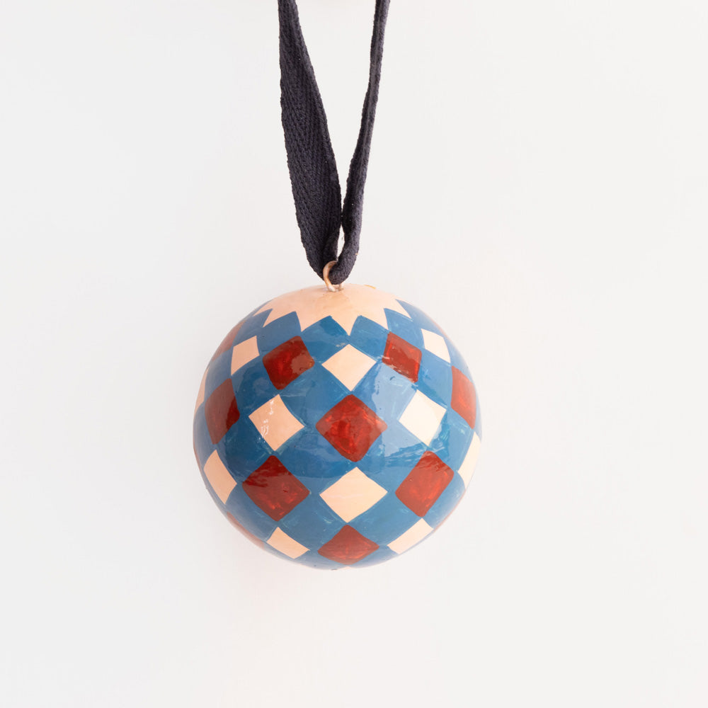 Blue, pale pink and red harlequin hand painted papier-mâché Christmas bauble with a navy ribbon hanging loop.