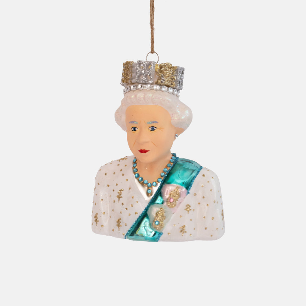 Glass bust ornament of an older woman with white curls, a jewelled crown, white gown with gold dots and a blue sash