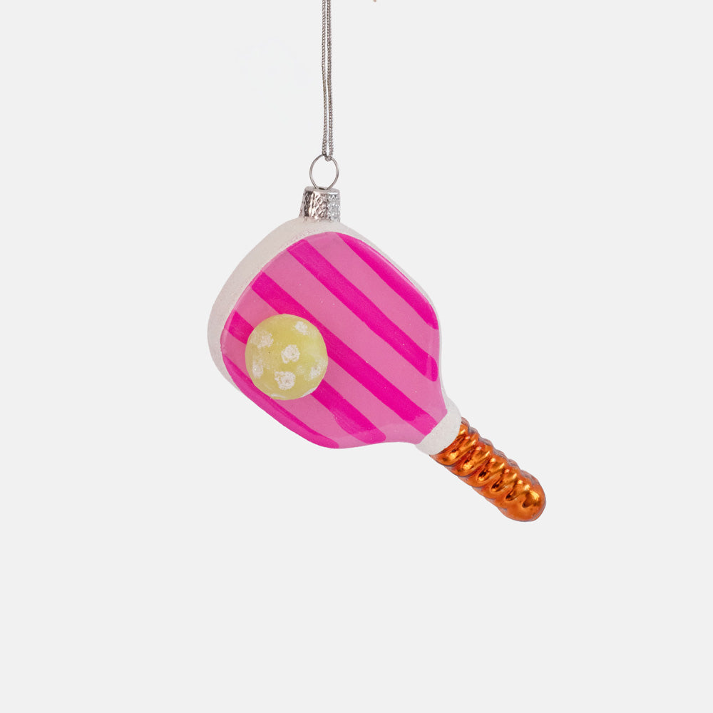 Pink striped glass ornament shaped like a pickleball paddle with an orange handle and a yellow ball