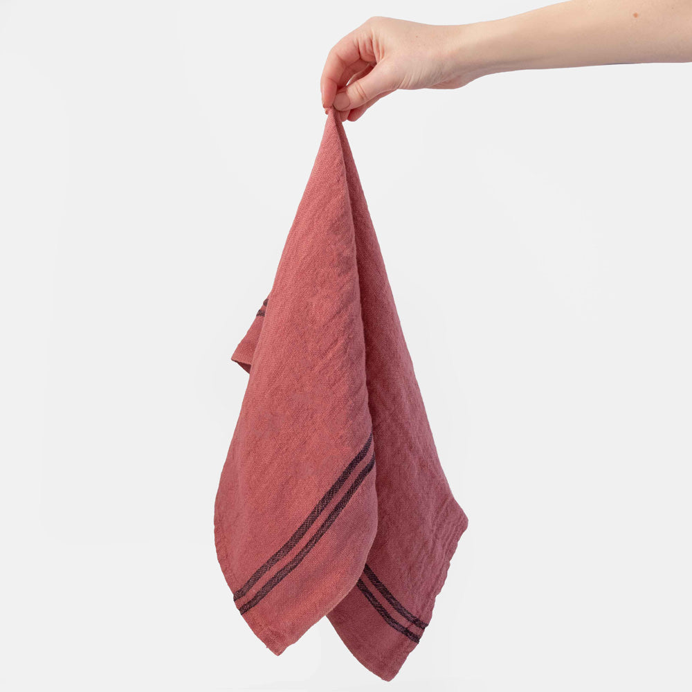 Hand holding a pink tea towel with a white background