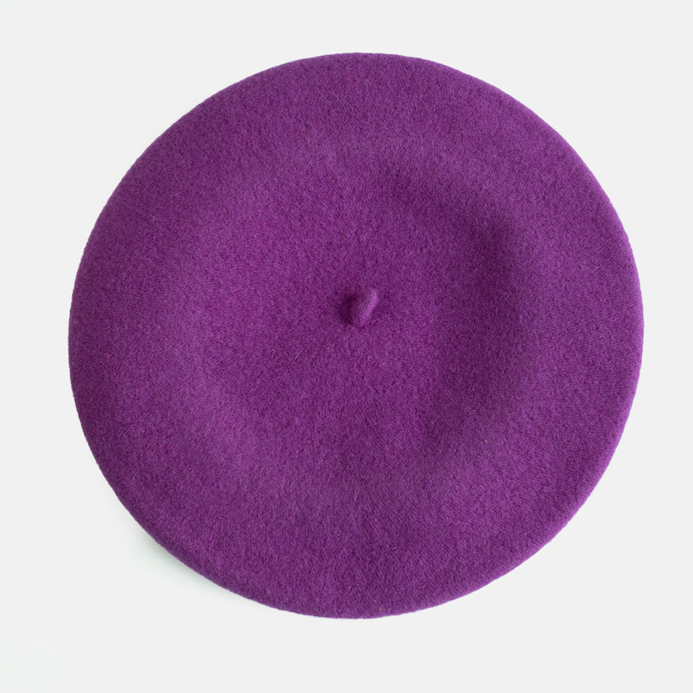 A top-down view of a solid purple felt beret hat on a clean white background.