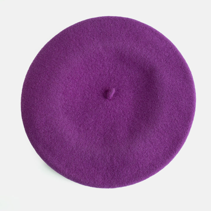 A top-down view of a solid purple felt beret hat on a clean white background.
