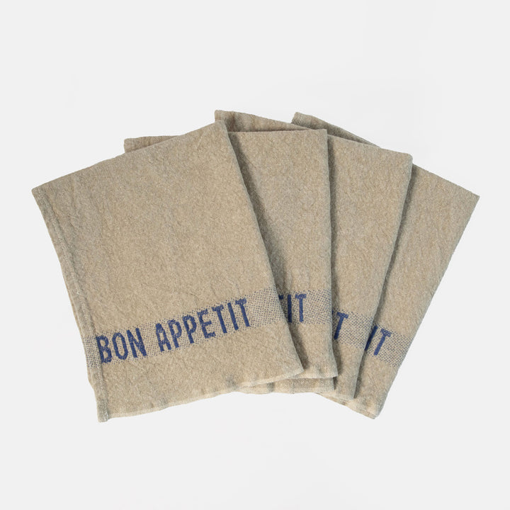 set of 4 beige napkins with blue 'bon appetit' design on a white background