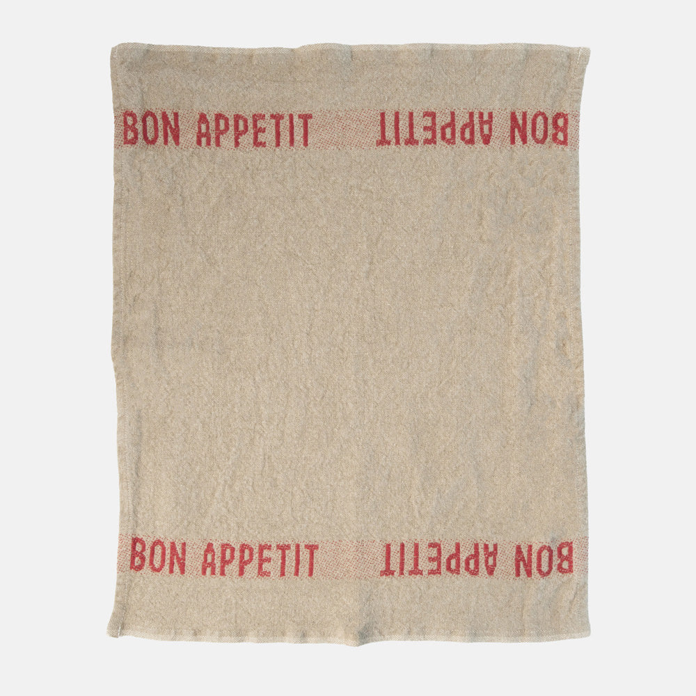beige napkin with red 'bon appetit' design on a white background