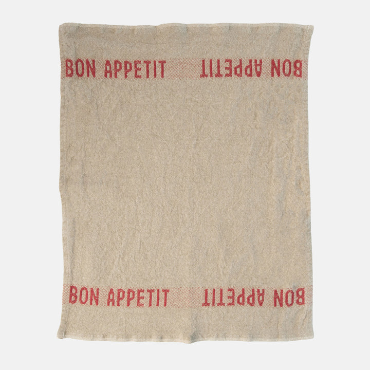 beige napkin with red 'bon appetit' design on a white background