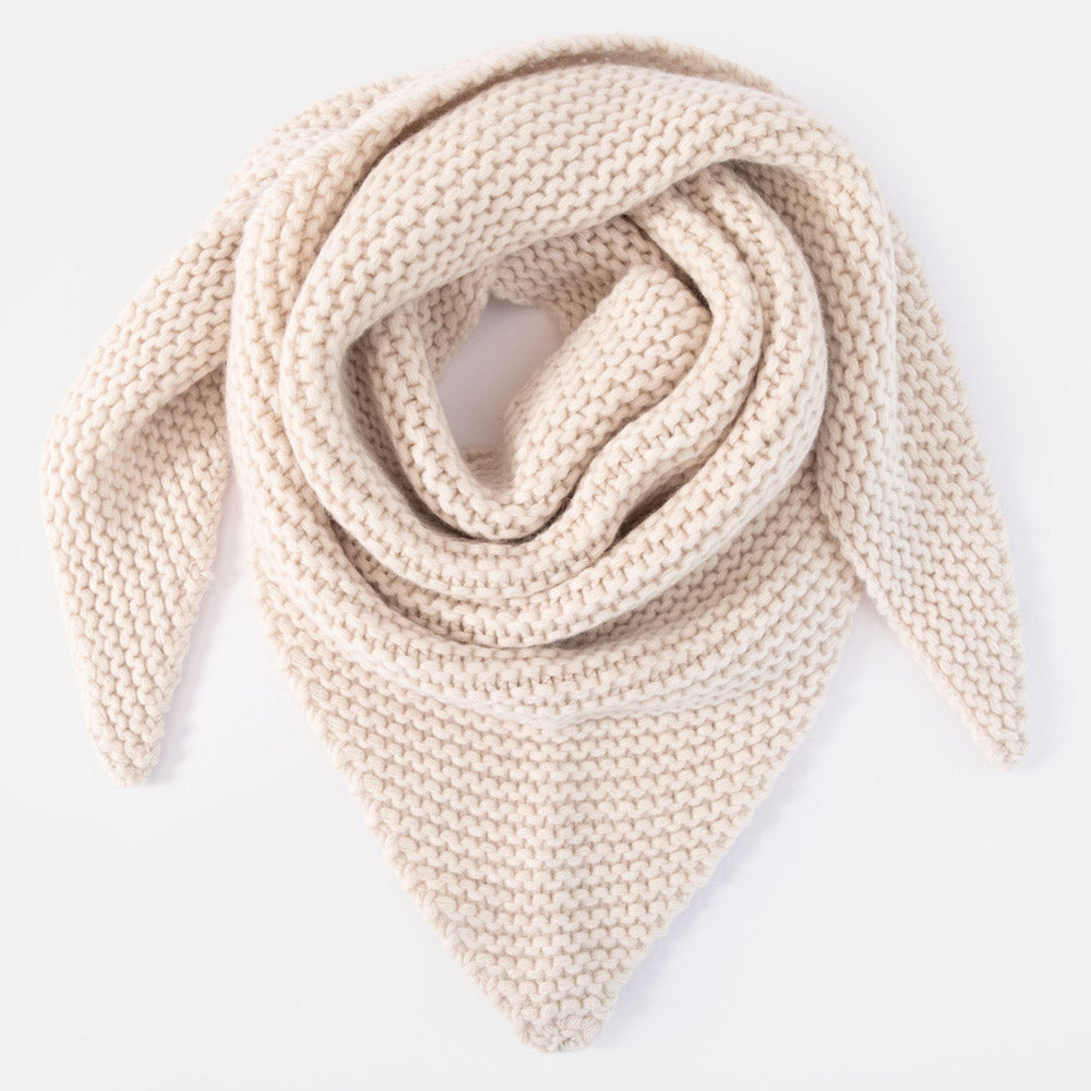 A chunky knit triangular scarf in a warm cream or oatmeal color, arranged in a neat spiral on a clean white background.