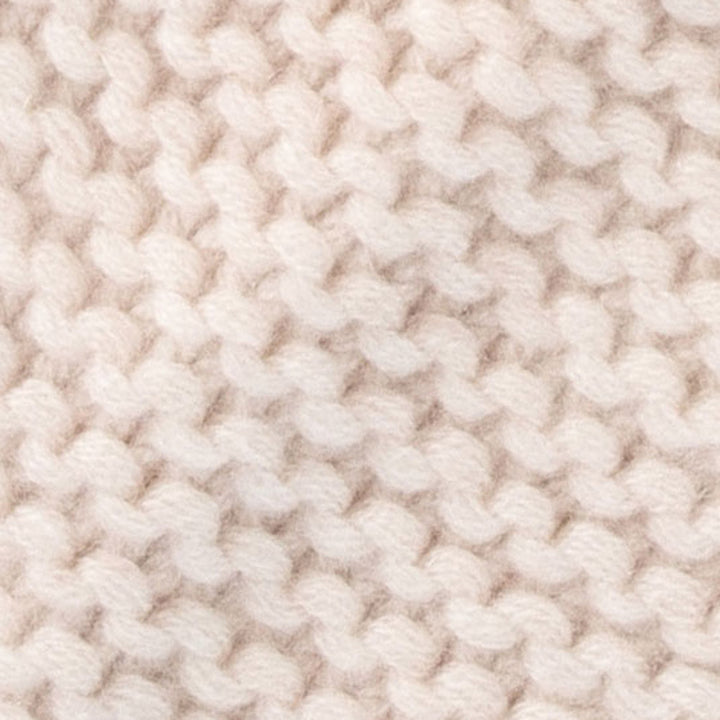 A close-up of a chunky knit fabric in a warm off-white or cream color, showing the detailed texture of the yarn stitches.
