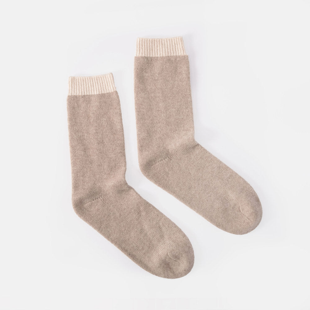 A pair of light taupe knit crew socks with ribbed cream cuffs, displayed on a clean white background.