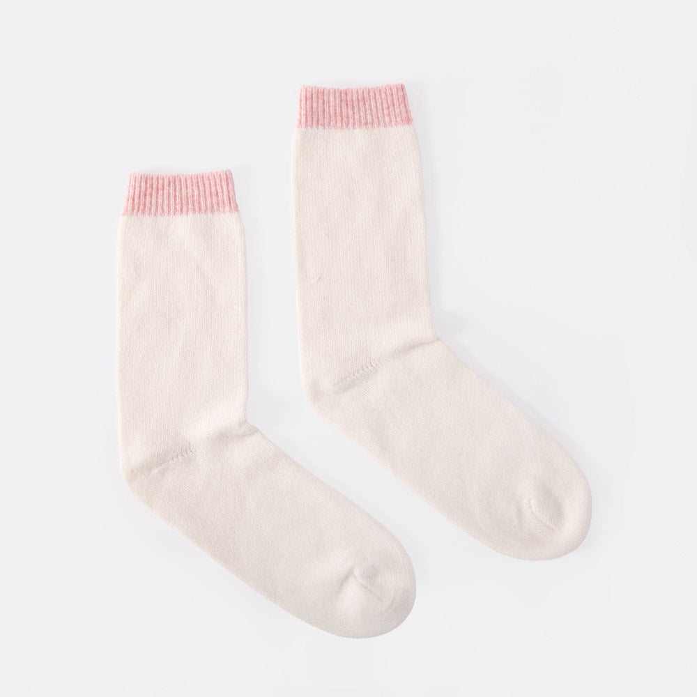 A pair of cream-colored crew socks with light pink ribbed cuffs, displayed on a clean white background.