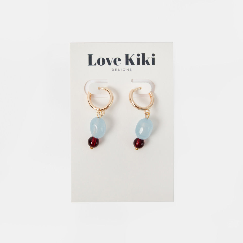 pair of gold hoop earrings with light blue and burgundy beads on a 'love kiki' branded backer