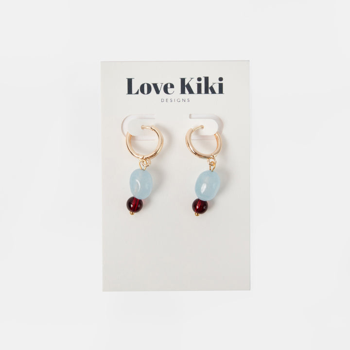 pair of gold hoop earrings with light blue and burgundy beads on a 'love kiki' branded backer
