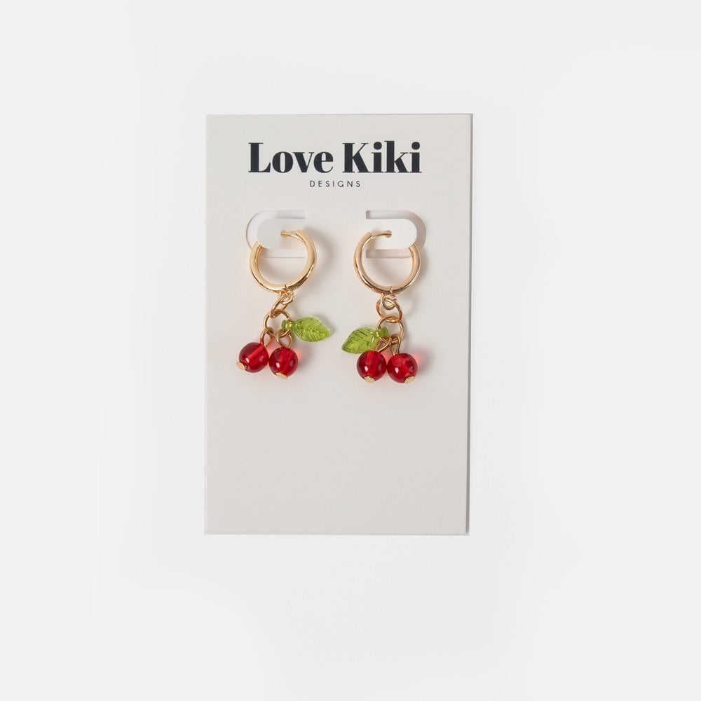 gold hoop earrings with red cherry shaped glass beads and green leaves on love kiki branded packaging