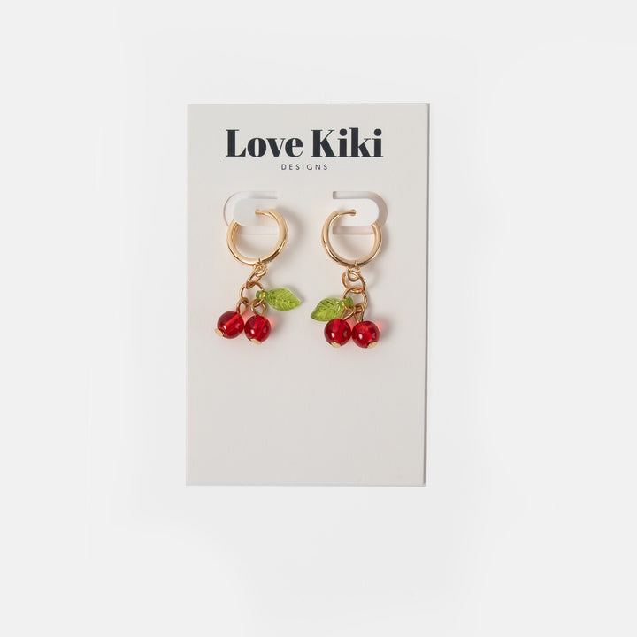 gold hoop earrings with red cherry shaped glass beads and green leaves on love kiki branded packaging