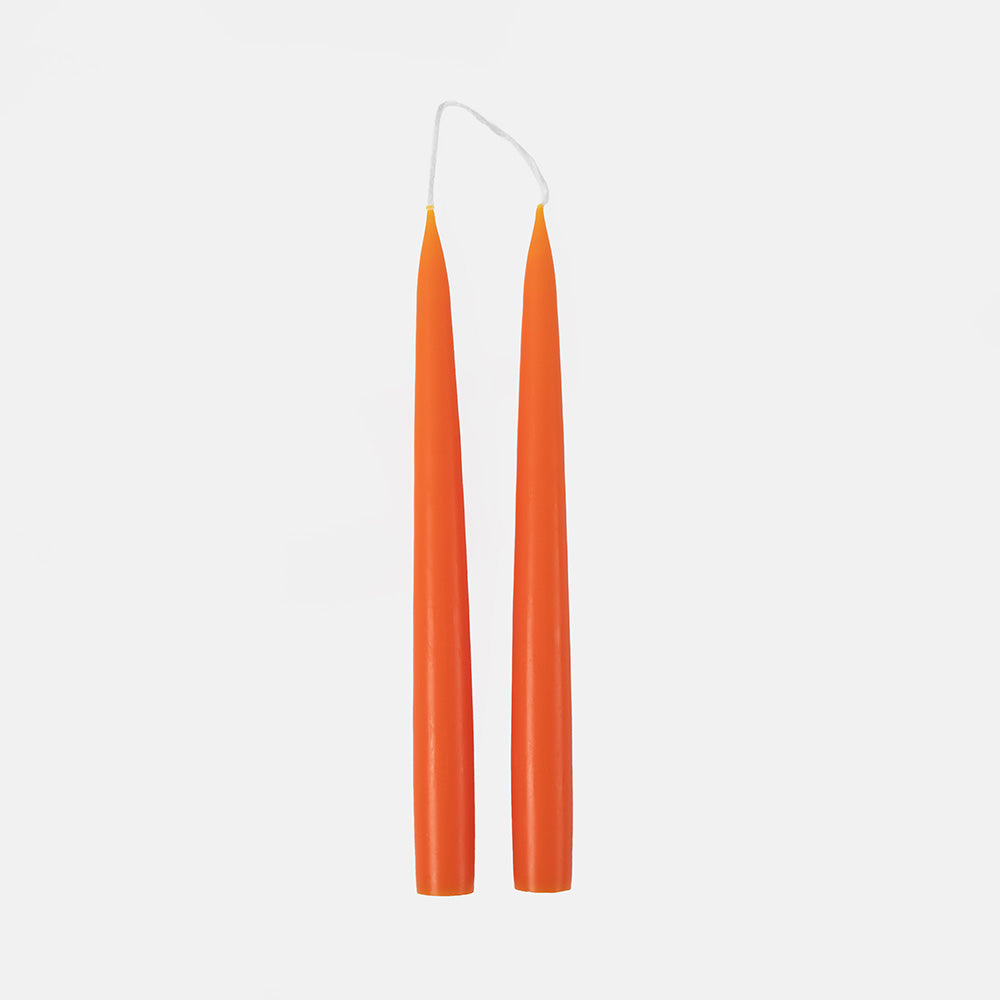 Two orange candles with white wicks on a light grey background