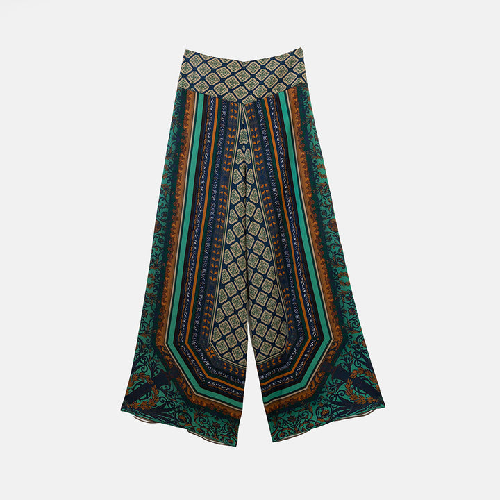 A pair of wide-leg palazzo pants featuring a complex geometric and tribal-inspired pattern in teal, navy, brown, and beige, displayed against a light gray background.