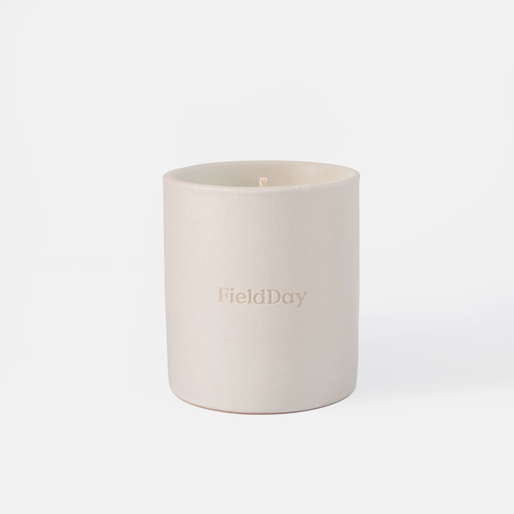A matte off-white ceramic candle jar with the brand name 'FieldDay' embossed on the front, set against a seamless white background.