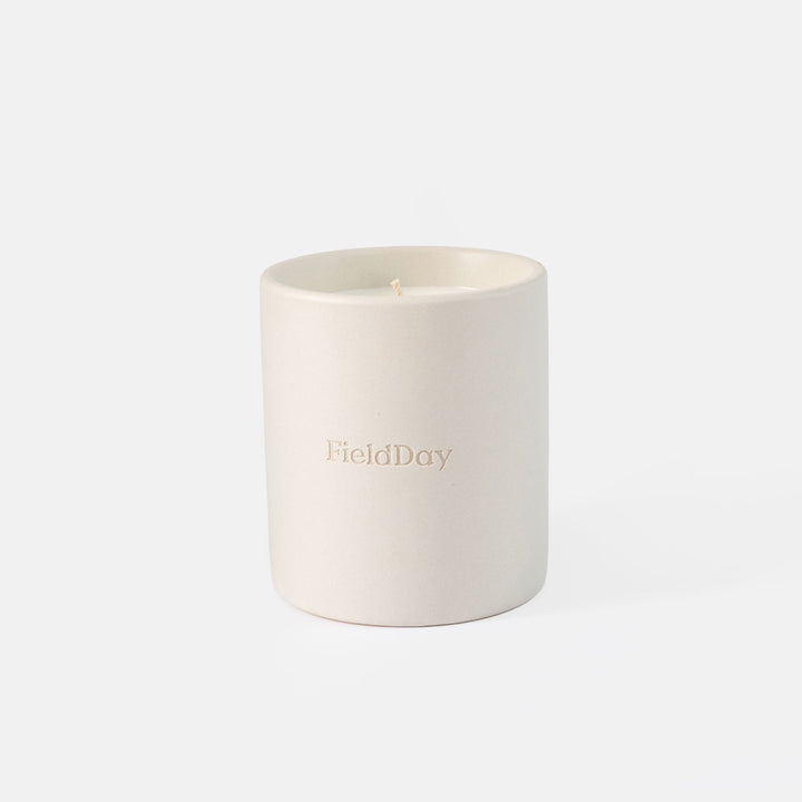 A matte off-white ceramic candle jar with the brand name 'FieldDay' embossed on the front, set against a seamless white background.