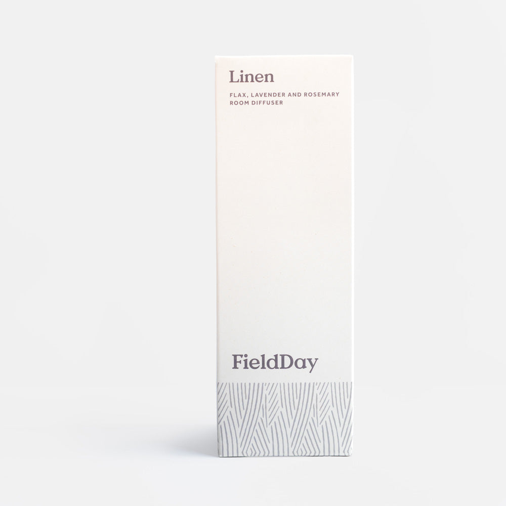 A tall, narrow white box for a FieldDay linen room diffuser, featuring minimalist gray text and a subtle gray patterned band at the bottom, set against a clean light gray background.